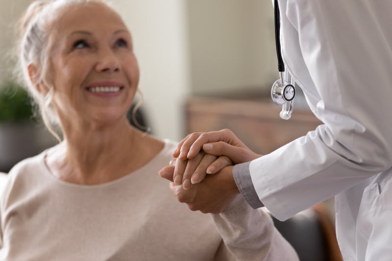 Doctor holding the hand of a happy senior woman