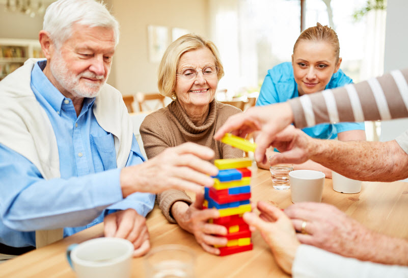 Group of seniors plays together with colorful building blocks in retirement home