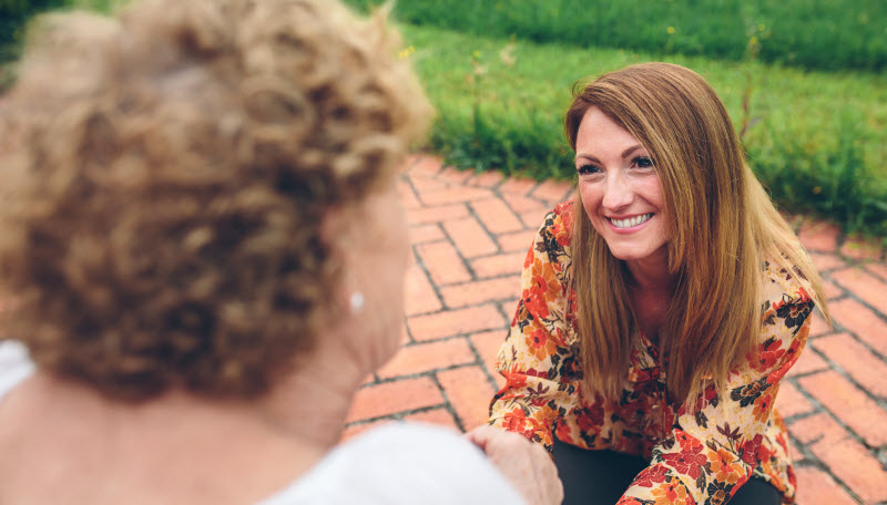 Happy young woman caring elderly woman in the garden