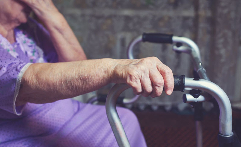 Hands of an elderly woman rests on on a walker.