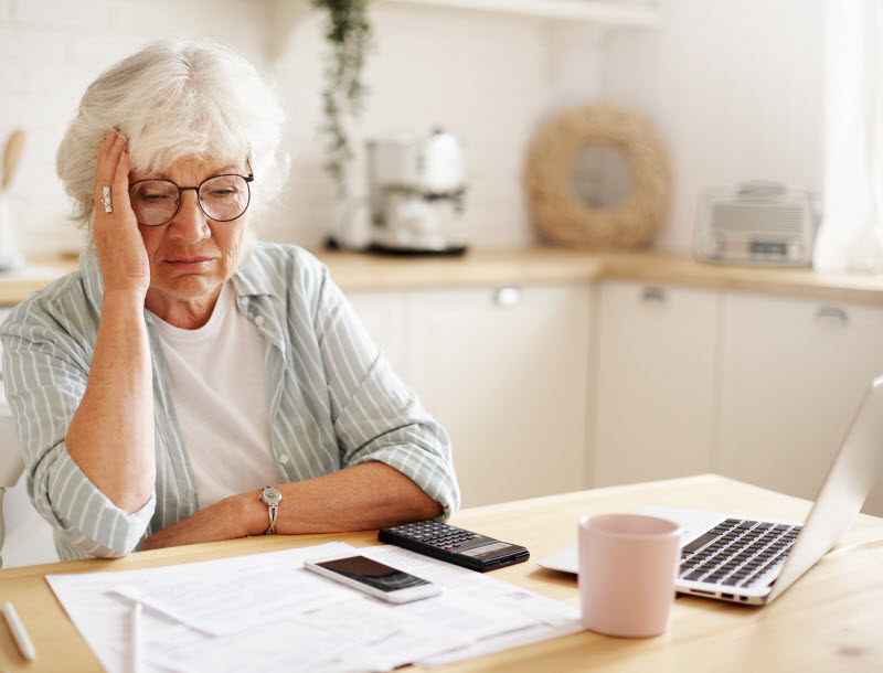 Stressed senior woman looking at the bills while in the dining table