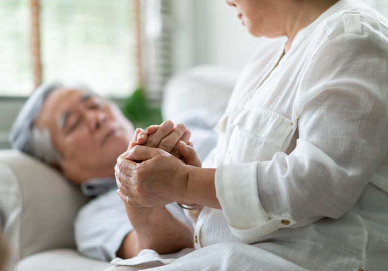 Asian Old Woman holding hand Senior man while laying down
