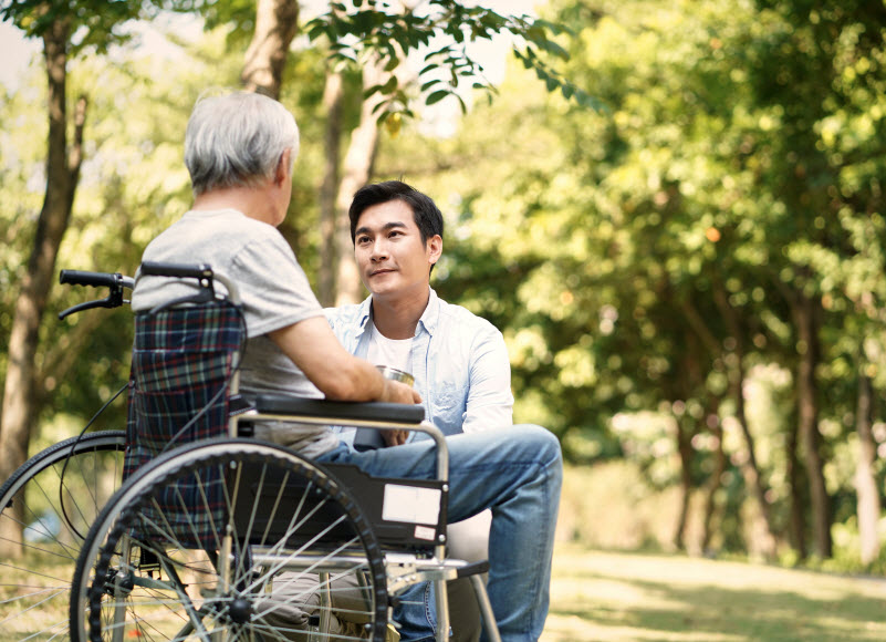 Son talking to and comforting wheelchair bound father